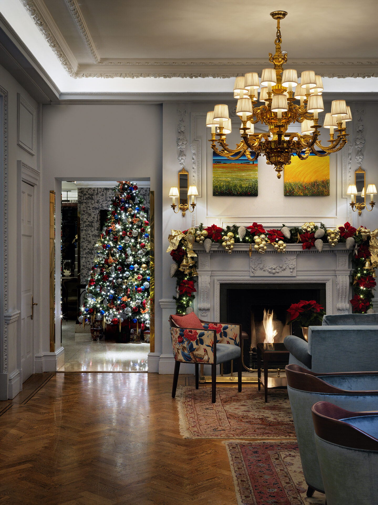 Luxurious hotel lounge with a Christmas tree, festive garlands, and a chandelier above a cosy fireplace