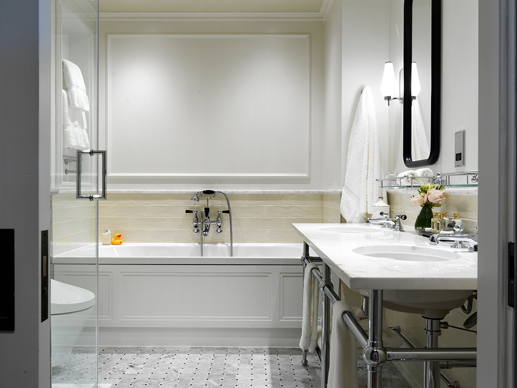 Modern bathroom with a white bathtub, marble countertop, and fresh flowers—perfect for a relaxing Mother's Day; neutral tones and bright lighting create a clean, elegant feel.