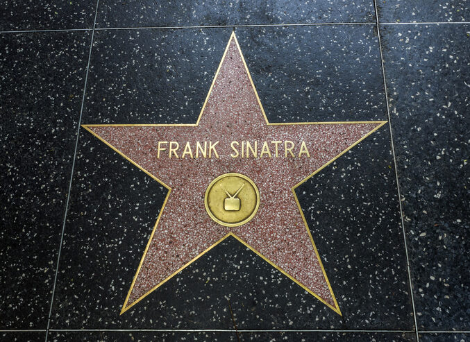 A pink terrazzo star with Frank Sinatra in gold letters on the Hollywood Walk of Fame, set in a speckled black sidewalk with a TV symbol in a gold circle at the bottom.