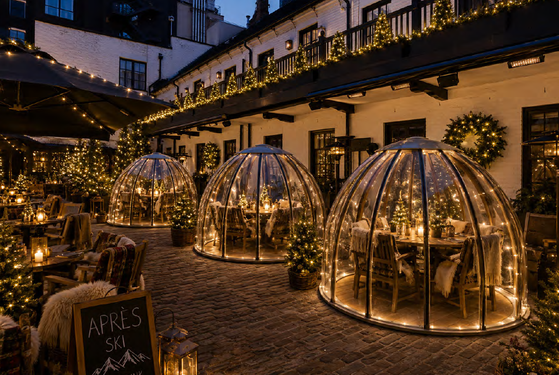 A cosy outdoor courtyard at night, featuring three glass dining domes decorated with fairy lights for Christmas, surrounded by festive greenery and warm glowing lanterns. A chalkboard sign reads Après Ski.